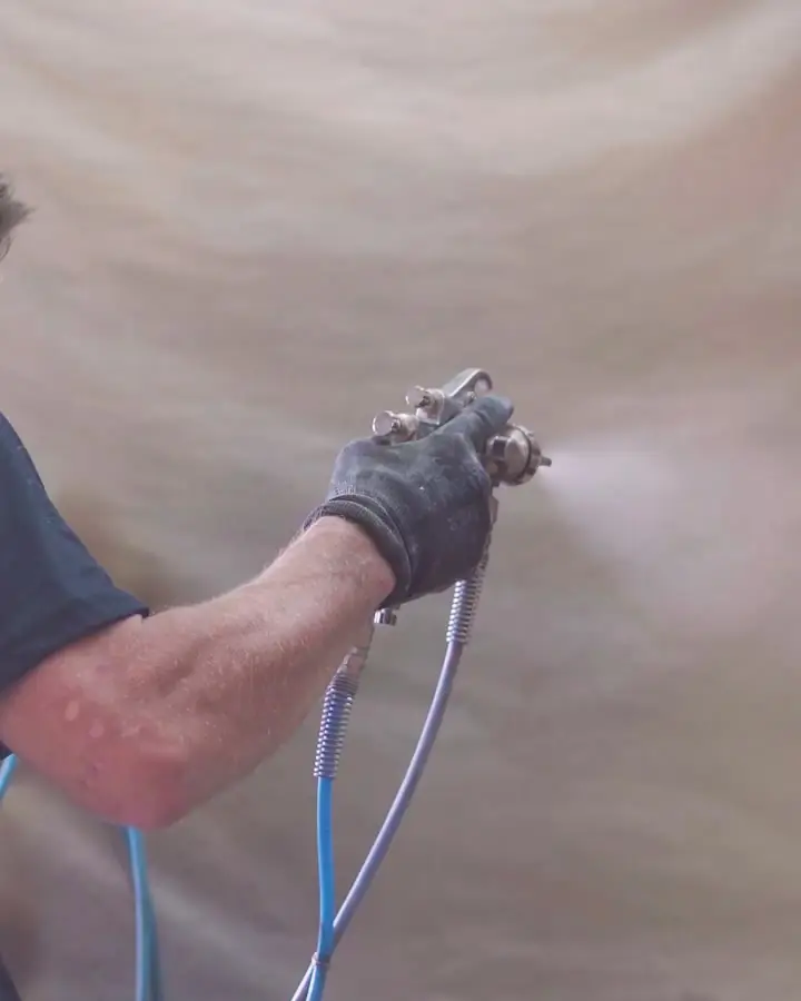 Funcionário aplicando verniz em uma cadeira na cabine de pintura